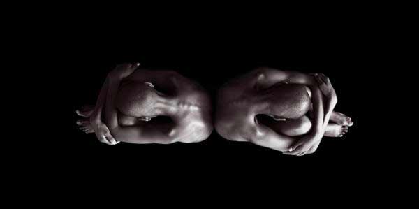 Photograph of twins sitting back-to-back, taken from above