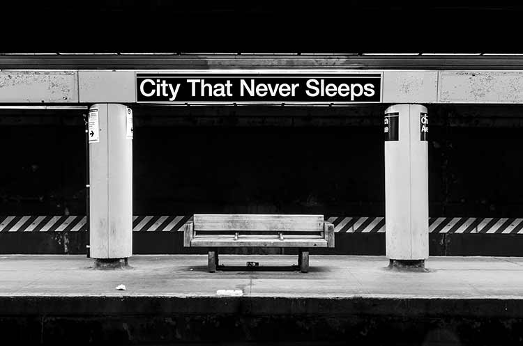 A black and white photograph of a subway bench