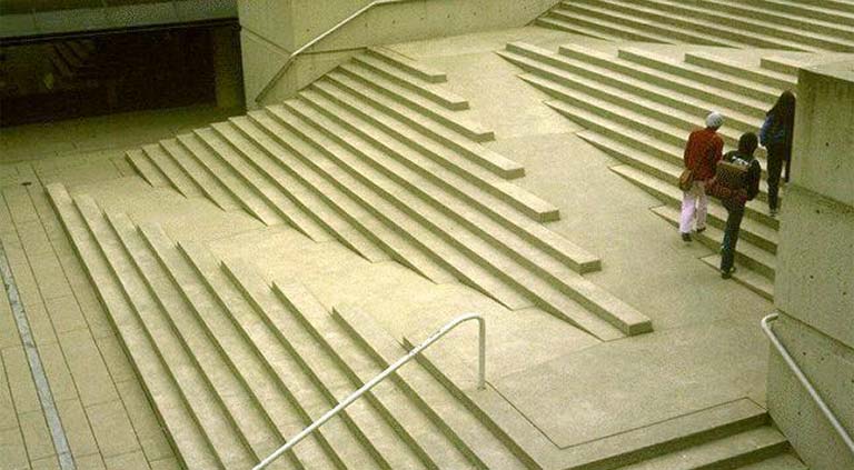 Photograph of people walking up a staircase with an integrated wheelchair access ramp